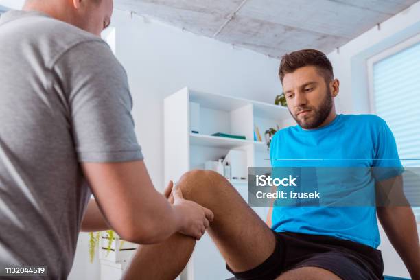 Physiotherapist Massaging Young Mans Legs Stock Photo - Download Image Now - Knee, Doctor's Office, Healthcare And Medicine