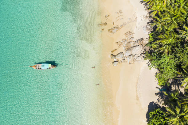 blick von oben, atemberaubender blick aus der luft auf einen wunderschönen tropischen strand mit weißem sand und türkisfarbenem wasser, langschwanzbooten und sonnenbaden, banana-strand, phuket, thailand. - strand patong stock-fotos und bilder