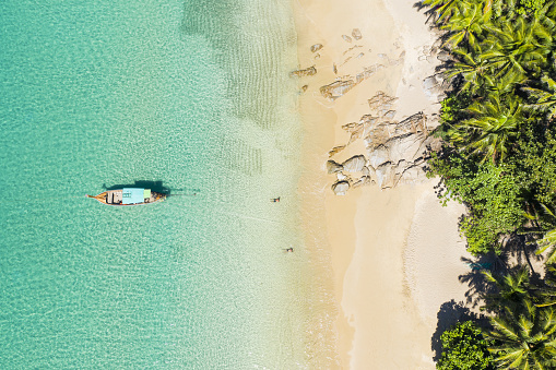Vista desde arriba, impresionante vista aérea de una hermosa playa tropical con arena blanca y agua cristalina turquesa, barcos Longtail y gente tomando el sol, Banana Beach, Phuket, Tailandia. photo