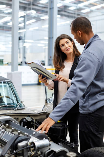 ingegnere e supervisore discutono sul motore dell'auto - automobile industry transportation indoors vertical foto e immagini stock