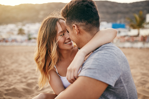 Pareja joven romántica sentada juntos en una playa de arena photo