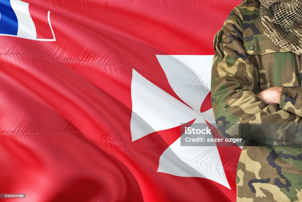 Crossed arms soldier with national waving flag on background - Wallis And Futuna Military theme. Alertness Stock Photo