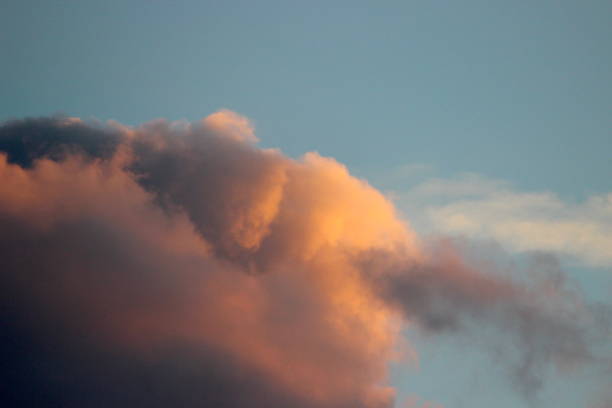 Colorful cloud Large cloud colored in warm colors by the setting sun on a wintry afternoon. weltall stock pictures, royalty-free photos & images