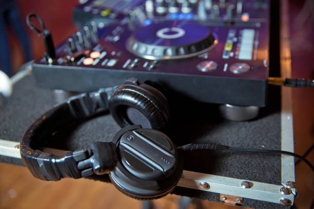 istock Professional dj headphones on cd player turntable deck in night club.Double exposure effect.Disc jockey audio equipment for parties.Play music,mix tracks on digital turntables hardware 1132052346
