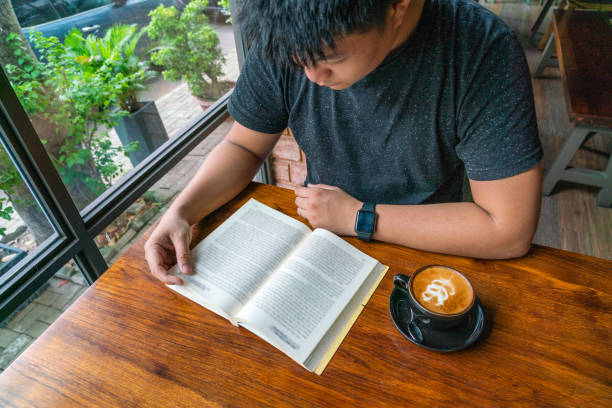Young man reading book in the cafe stock photo