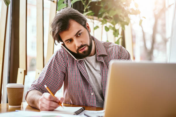 istock Opportunities don't happen. You create them. Horizontal shot of male office worker making notes with pen in his notebook at co-working space. Pensive manager sitting in creative office 1132053920