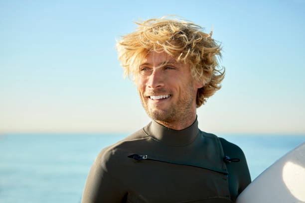 istock Smiling male surfer looking away at beach 1132054031