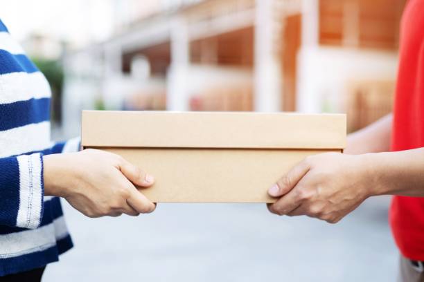 istock parcel delivery man of a package through a service. and close up hand customer accepting a delivery of boxes from delivery man postal. 1132056840