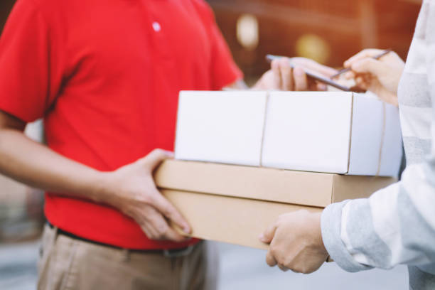 istock parcel delivery man of a package through a service. and close up hand customer accepting a delivery of boxes from delivery man postal send direct to home. 1132056843