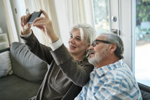 istock Elderly woman taking selfie with man at home 1132057516