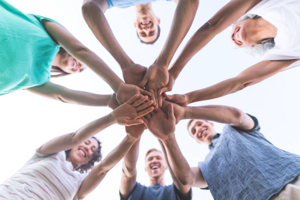 A multiethnic group puts their hands together for a 
