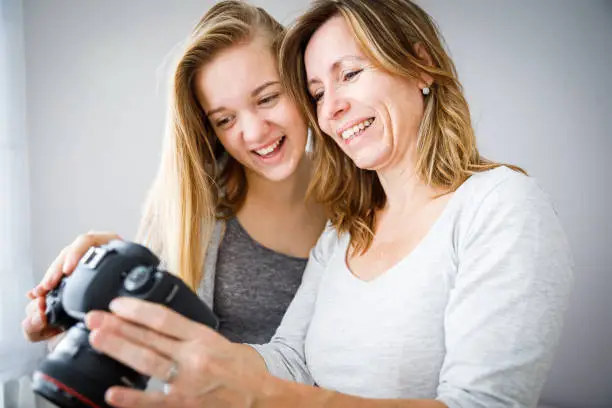 Mother and daughter taking photos and checking them on a modern digital DSLR camera