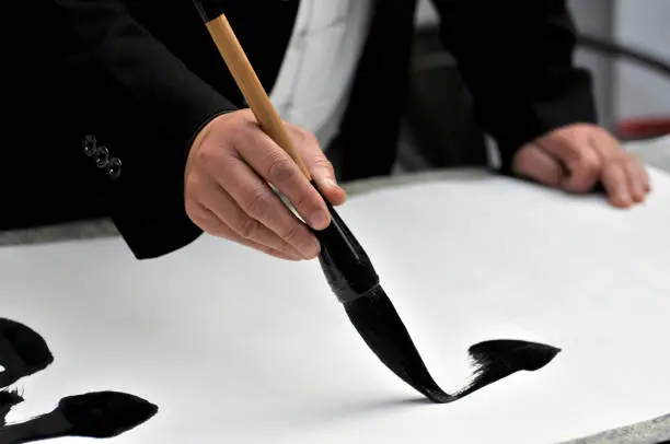 Photo of Hand with brush painting Chinese calligraphy