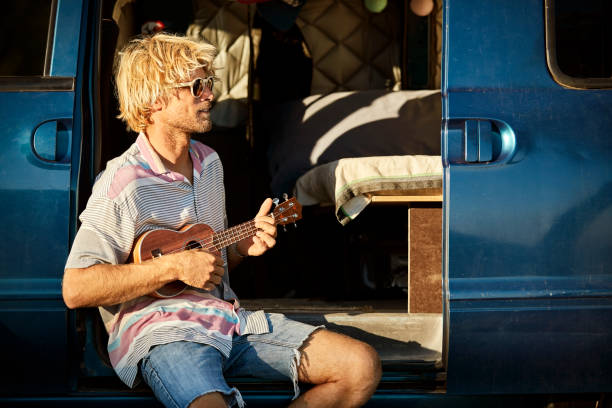 istock Man playing acoustic guitar in mini van doorway 1132059927