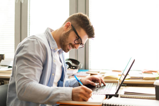 homem novo na biblioteca no portátil - clothing casual concepts concentration - fotografias e filmes do acervo