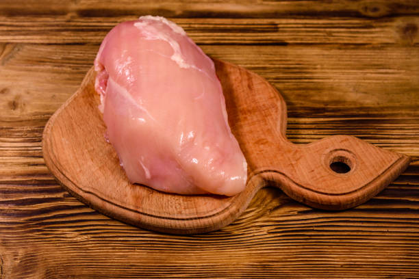 istock Cutting board with raw chicken fillet on wooden table 1132066798