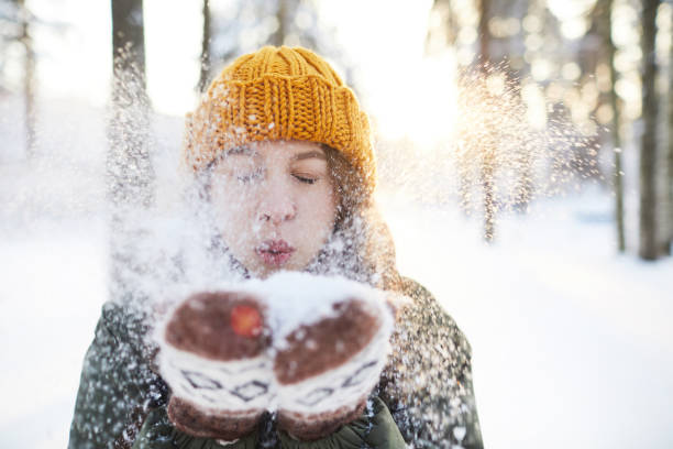 Fun in Winter Park Portrait of happy young woman playing with snow in winter, blowing snowflakes to camera, copy space swedish woman stock pictures, royalty-free photos & images