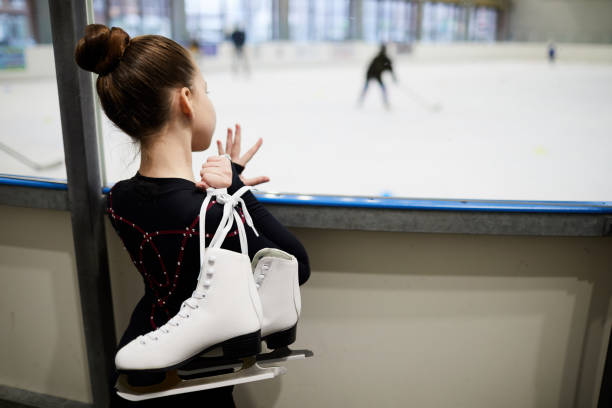 Dream of Figure Skating Back view portrait of future figure skater standing by ice rink and watching training, copy space figure skating stock pictures, royalty-free photos & images