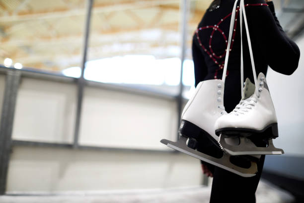 Girl Holding Figure Skates Closeup of unrecognizable girl holding figure skates over shoulder leaving ice rink after sports training, copy space figure skating stock pictures, royalty-free photos & images