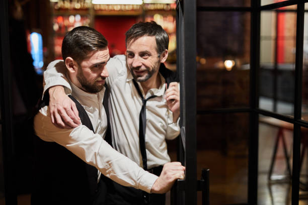 Drunk Man Leaving Pub Waist up portrait of waiter carrying drunk man out of bar at night, copy space drunk stock pictures, royalty-free photos & images