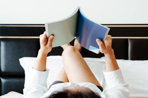 istock woman lay on bed reading the blank book 1132071744