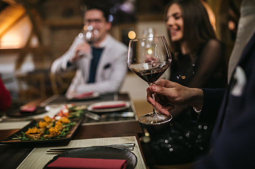 Close up of man's hand holding a glass of red wine in restaurant, unrecognizable person