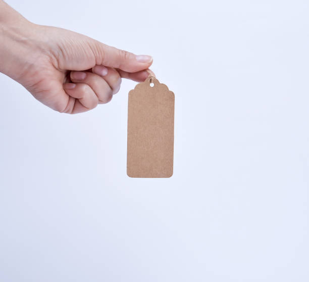 istock female hand holding a paper brown blank tag 1132075497