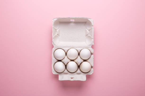 istock Six white eggs in carton box on pink paper background Top view Symbol Happy Easter Flat lay 1132076868