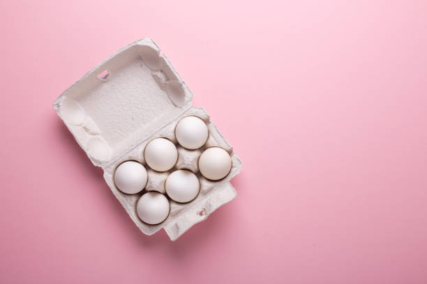 istock Six white eggs in carton box on pink paper background Top view Symbol Happy Easter Flat lay 1132076896