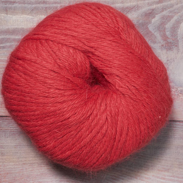 istock Red knitting thread on a wooden background 1132079982