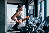 Side view of beautiful muscular woman running on treadmill.