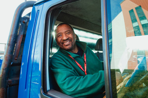 Happy Truck Driver Senior truck driver is smiling while pulling out of a parking lot in his work truck. old truck stock pictures, royalty-free photos & images
