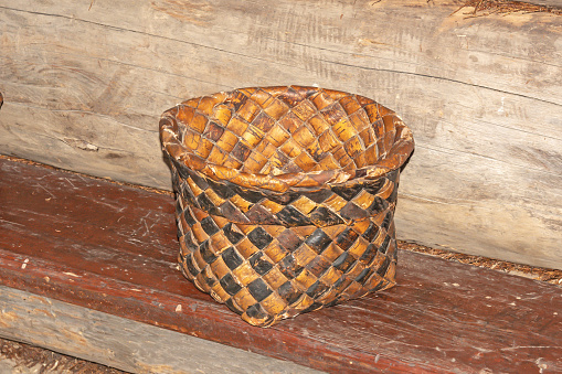 Old birch bark basket stands on a wooden bench