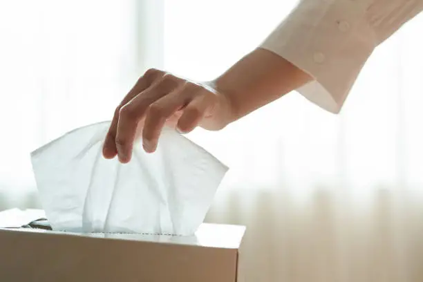 Photo of women hand picking napkin/tissue paper from the tissue box