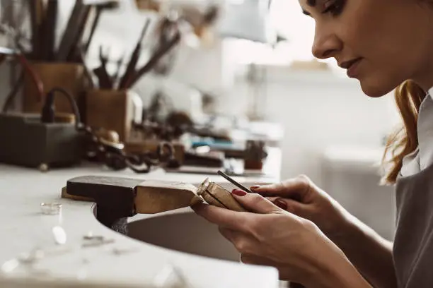 I got my inspiration. Side view of a female excited jeweler creating a silver ring at her workbench. Making accessories. Jewelry making process. Jewelry equipment. Working process. Jewelry manufacturing concept.