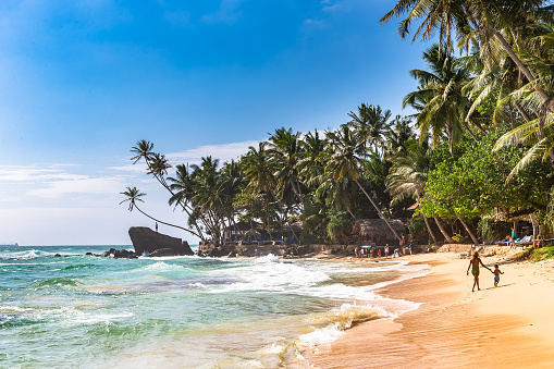 Unawatuna, Sri Lanka - December 23, 2018: People relaxing on beach in Unawatuna, Sri Lanka.