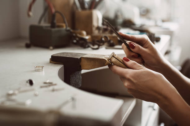 istock Master's hands. Side view of a female jeweler hands creating a silver ring at her workbench. Making accessories 1132088783