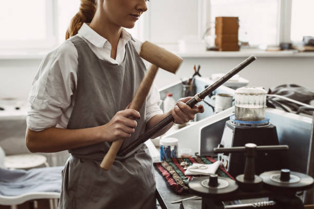 istock Making right size. Side view of female jewelry designer bending a silver blank on road using a mallet hammer 1132088807