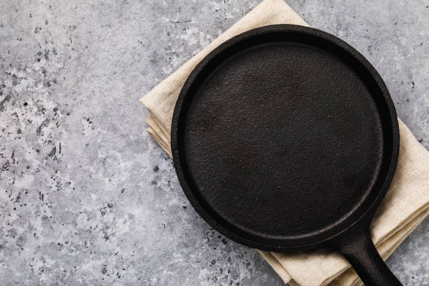 istock Black cast iron pan with a napkin on the table. Food background 1132089094