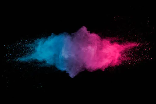 Photo of Explosion of multicolored dust on black background.