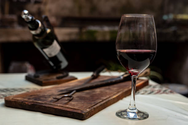 istock Wooden board with a fork for cooking a barbecue, a knife with a bone handle resting on a white table with a pampa protector on its side, a glass and a bottle of wine 1132092369