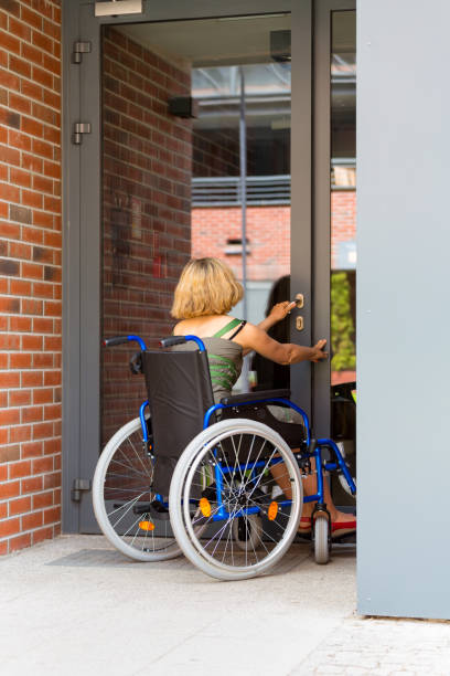 woman on wheelchair entering the building stock photo