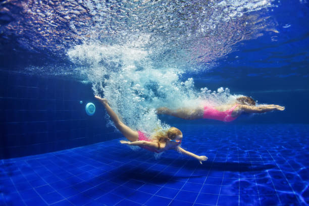 istock Child with mother dive in swimming pool 1132096268
