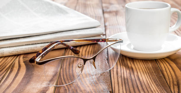 istock Eyeglasses with newspapers and cup of coffee on the table. 1132097967