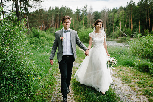 Attractive couple newlyweds on track in the garden. Outdoors. Romantic wedding moment.