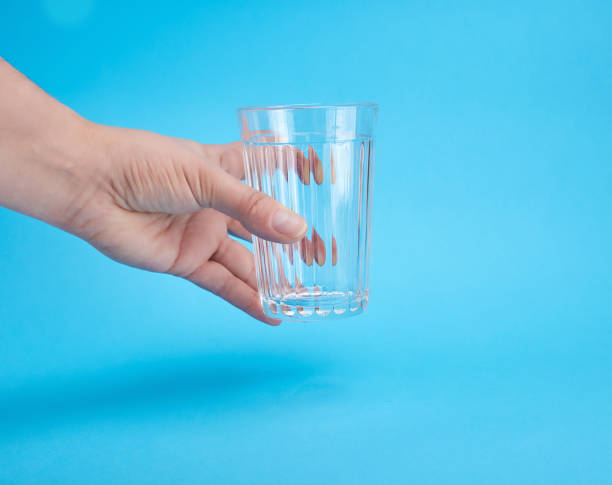 istock woman's hand holding an empty transparent glass 1132100560