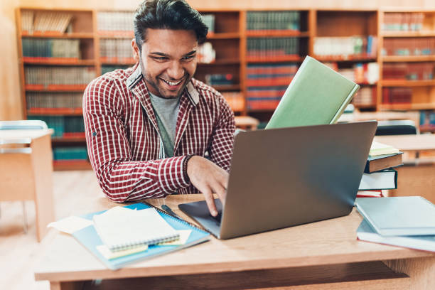 istock Smiling student with laptop and textbooks in the library 1132102630