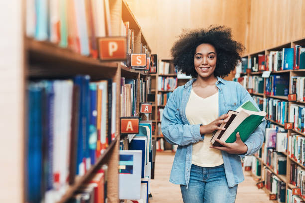 smiling african ethnicity student in the library - library young adult bookstore people imagens e fotografias de stock