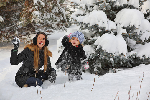 Mother and young daughter playing in snow in Minnesota