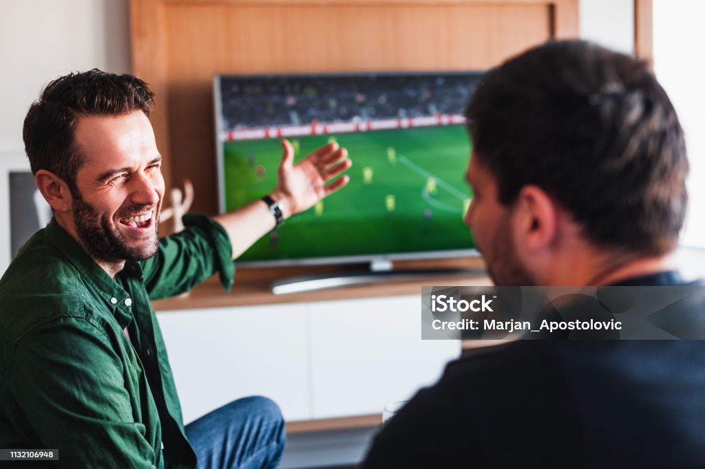 Two guys drinking beer watching football Television Set Stock Photo